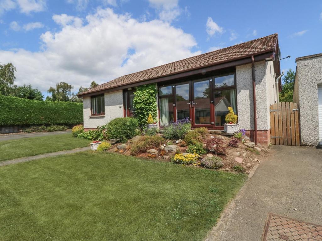 ein Haus mit großen Fenstern und einem Hof in der Unterkunft Isla Cottage in Rattray