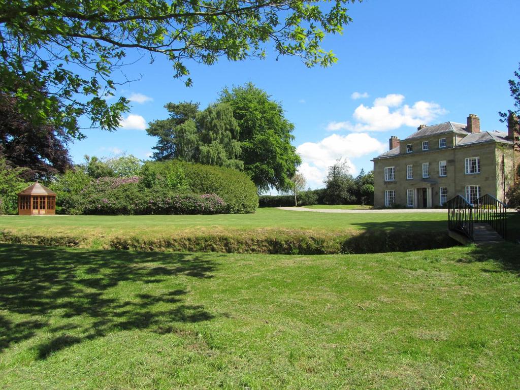 an old house with a lawn in front of it at Plas Yolyn in Ifton Heath