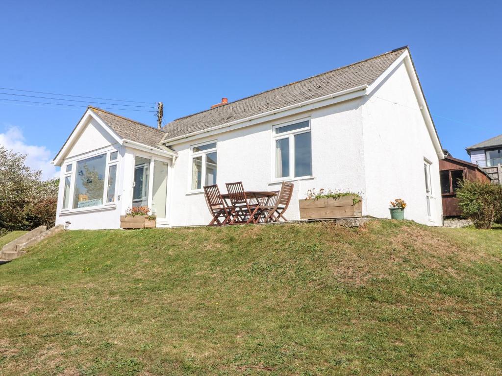 a white house with chairs and a table on a hill at Highdown in Bigbury on Sea