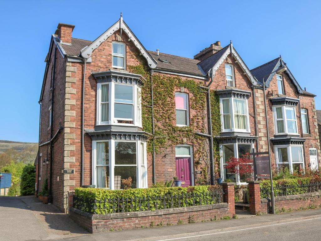 a red brick house with ivy on it at Talbot House in Castleton