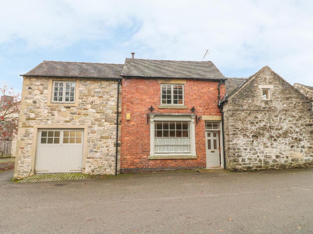 an old brick house with two garage doors at The Old Shop in Parwich