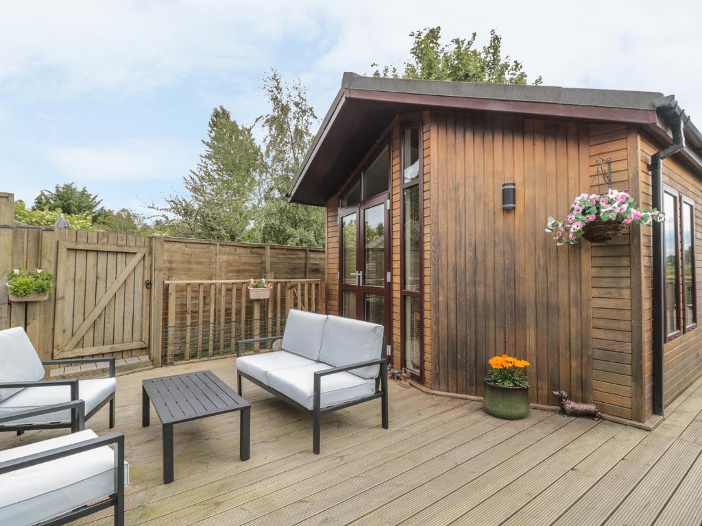a deck with a cabin with chairs and a table at Little Gem Lodge in Saint Boswells