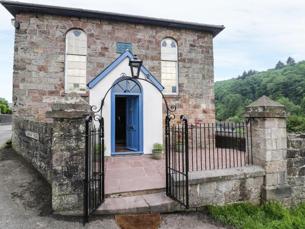 stary kamienny kościół z niebieskimi drzwiami w obiekcie Rainforest Chapel w mieście Longney
