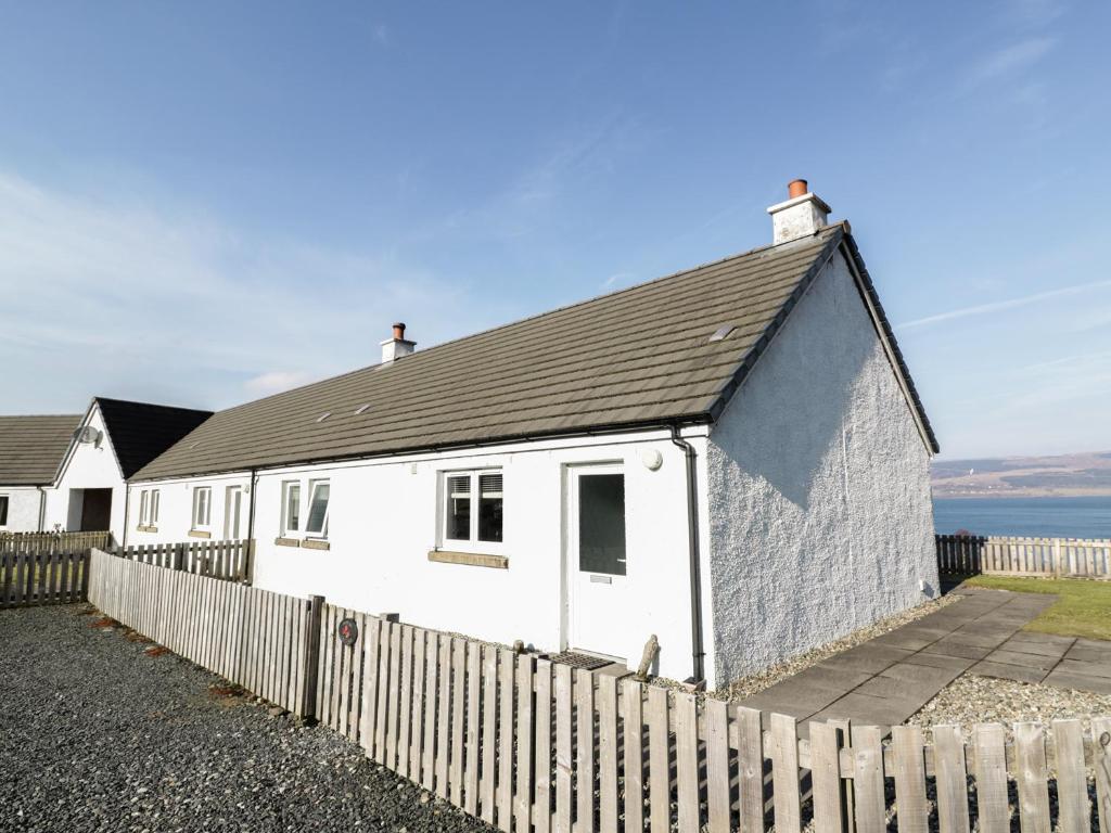 una casa blanca con una valla delante en Poppies Cottage, en Craignure