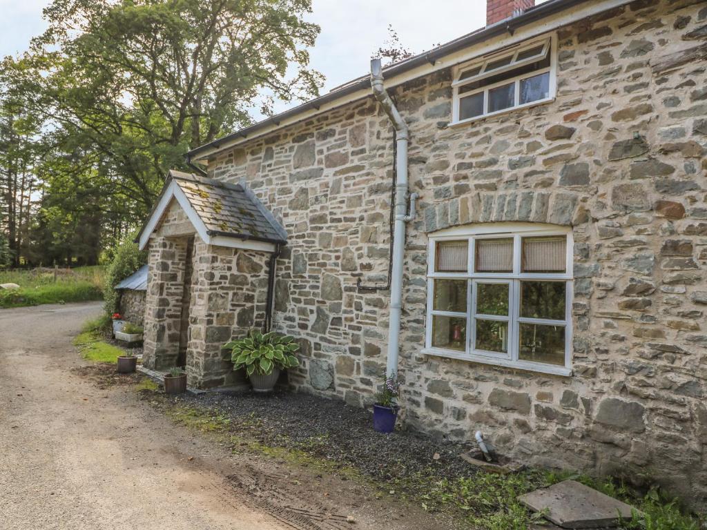 ein altes Steinhaus mit einem Fenster und einem Schuppen in der Unterkunft Preacher's Cottage in Llanbadarn-fynydd