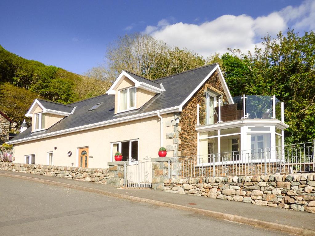 a white house with a stone wall at Arnant in Barmouth