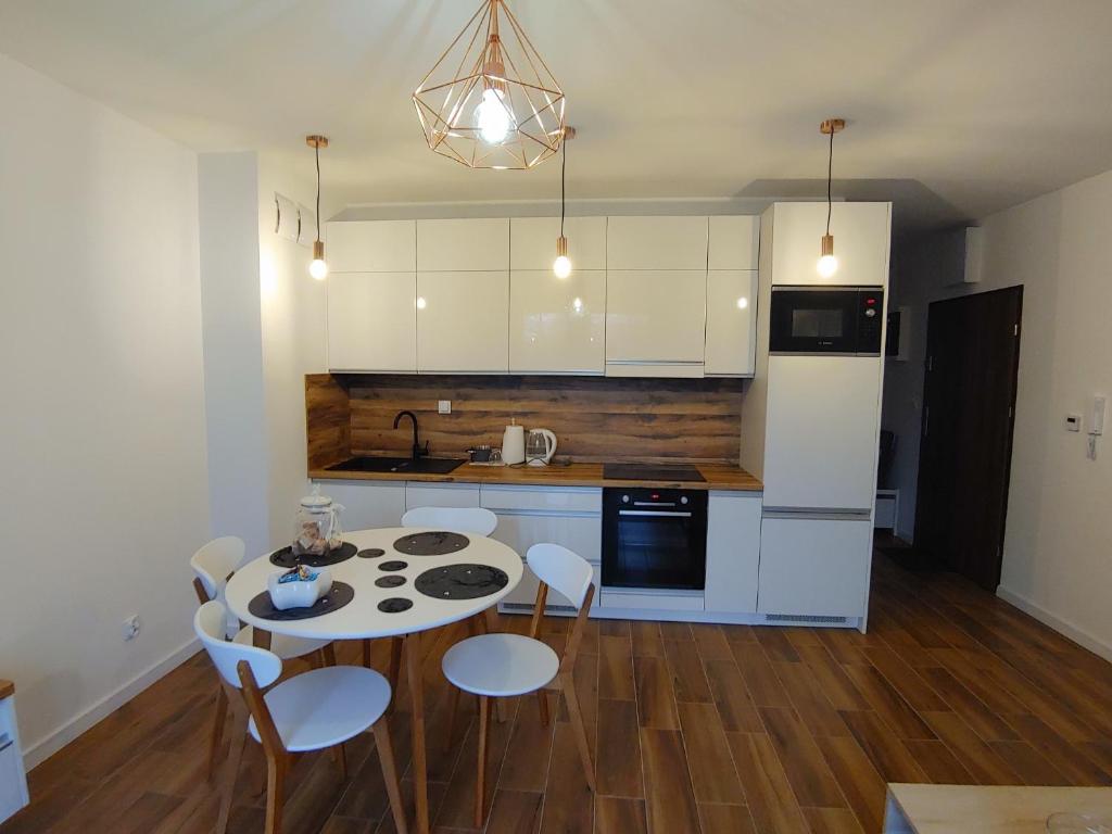a kitchen with a table and chairs and a kitchen with white cabinets at Cienista Myślibórz AN in Myślibórz
