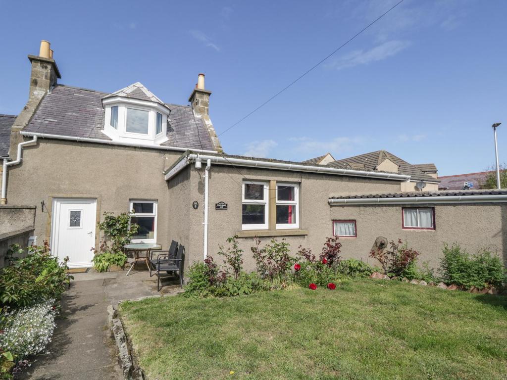 een huis met een tuin met een tafel en stoelen bij Fishermans Rest in Burghead