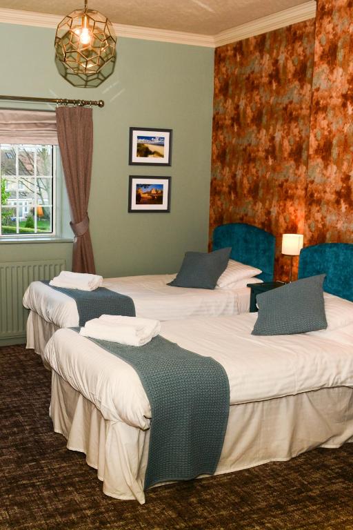 a group of four beds in a room at Plough Inn in Morpeth