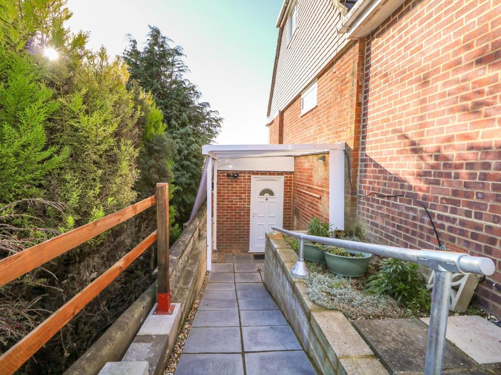 a brick building with a white door and a fence at 5 Firle Road Annexe in Lancing