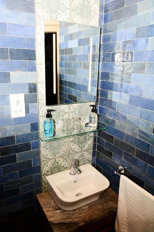 a blue tiled bathroom with a sink and a mirror at Plough Inn in Morpeth