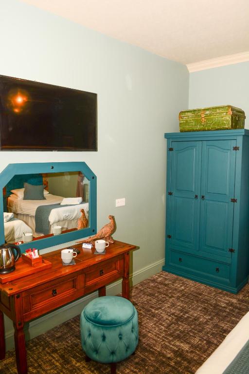 a bedroom with a blue cabinet and a mirror at Plough Inn in Morpeth