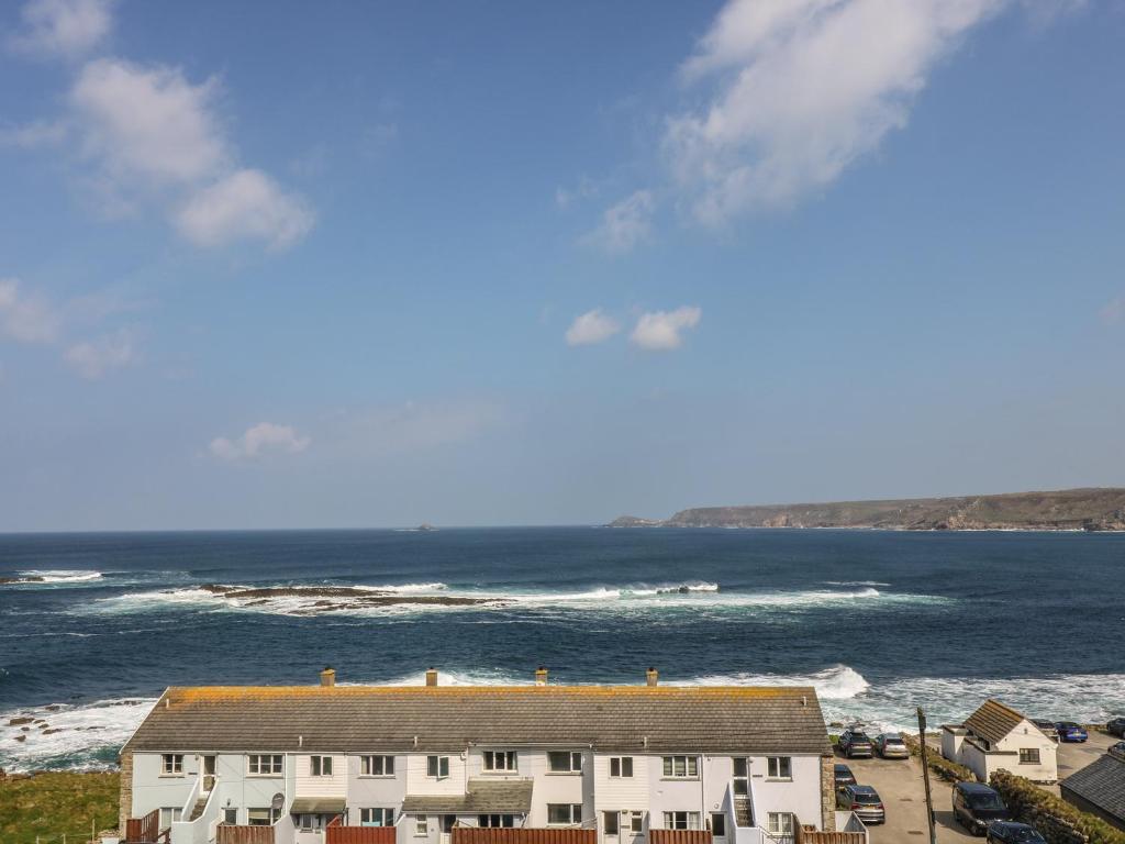 a house on the beach with the ocean in the background at Sennen Heights in Sennen Cove