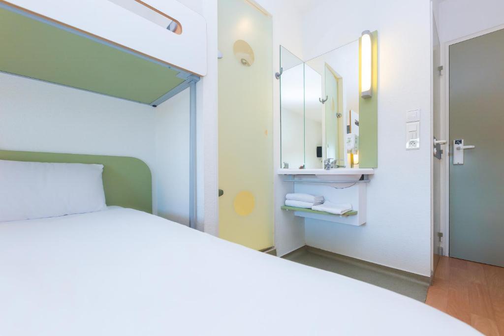 1 dormitorio con cama blanca y espejo en ibis budget Bergerac en Bergerac