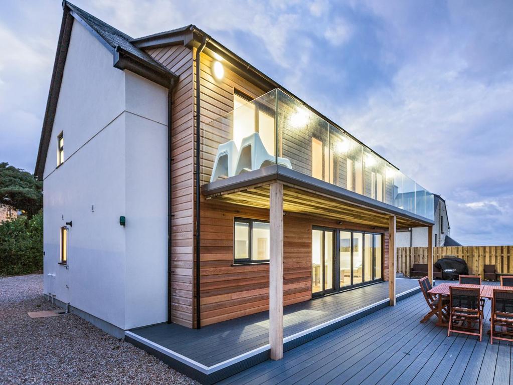 una casa de madera con una mesa en la cubierta en Chy Lowen, en St Ives