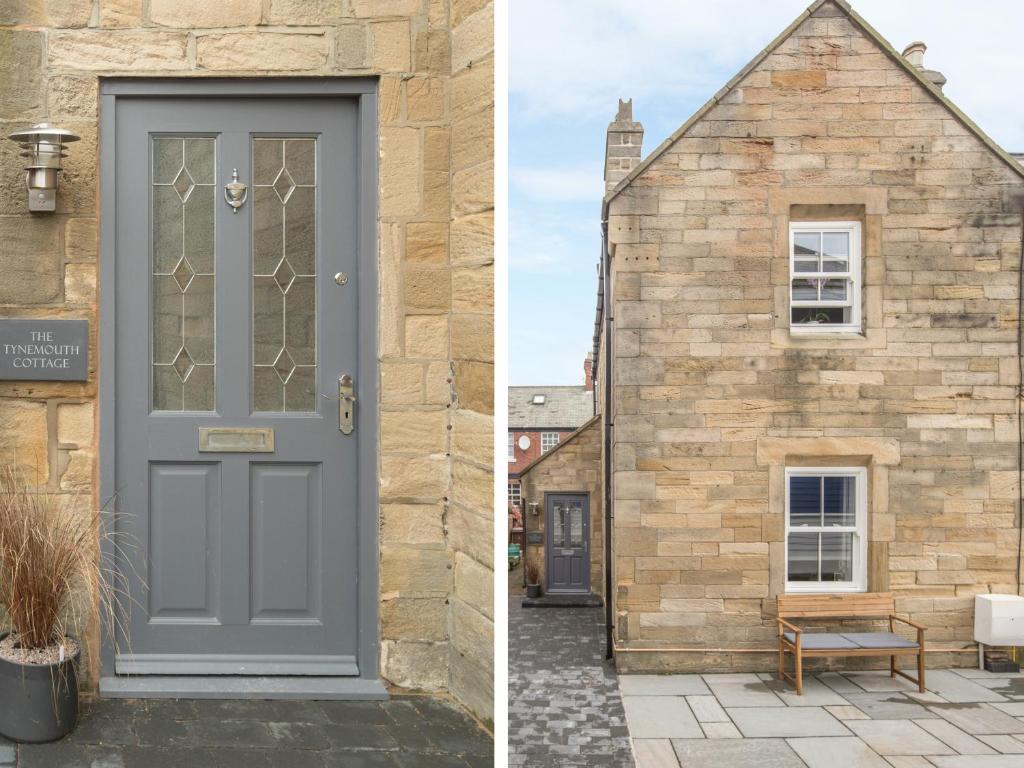 a house with a grey door and a building with a bench at The Tynemouth Cottage in Tynemouth