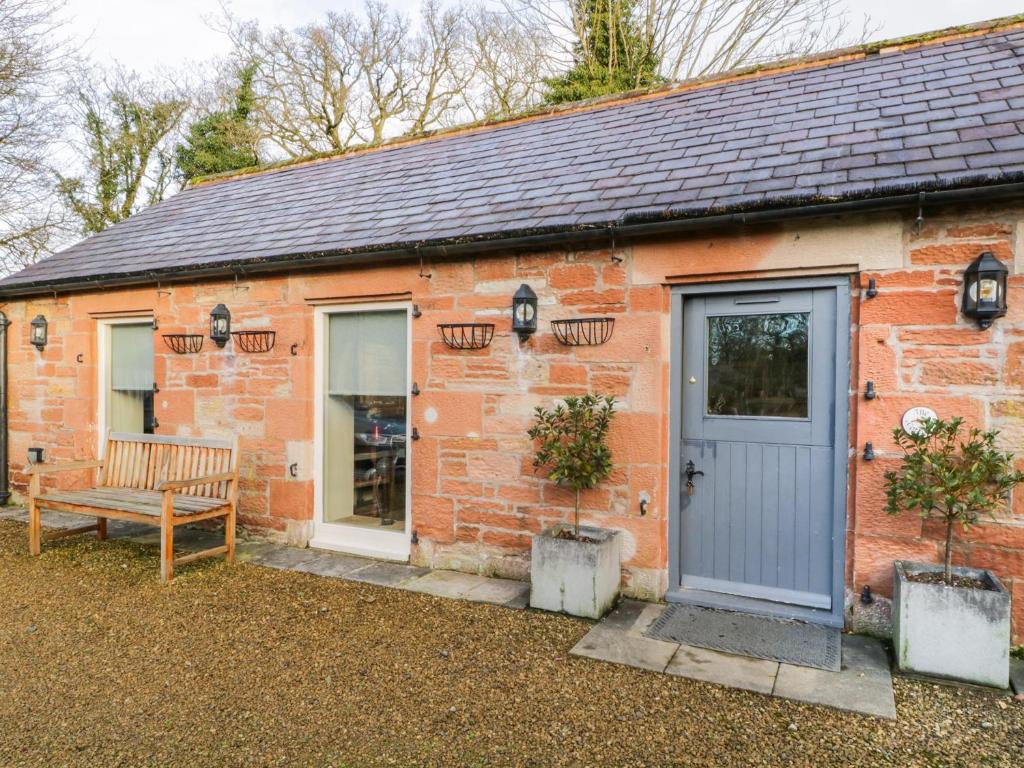 a brick cottage with a blue door and a bench at Carwinley Mill House Cottage in Canonbie