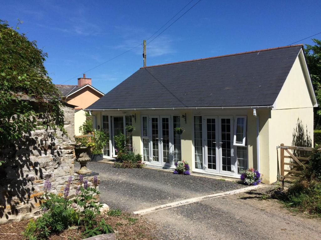 una casa blanca con un muro de piedra en The Coach House, en Bodmin