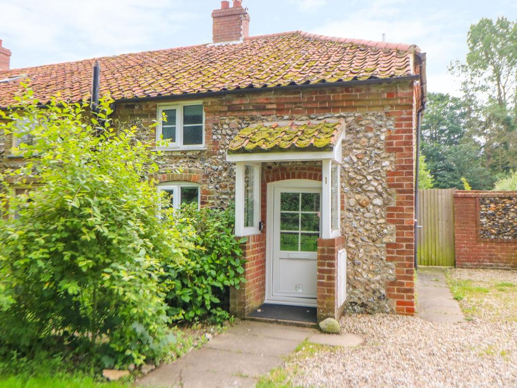 een rood bakstenen huis met een witte deur bij Broom Cottage in East Rudham