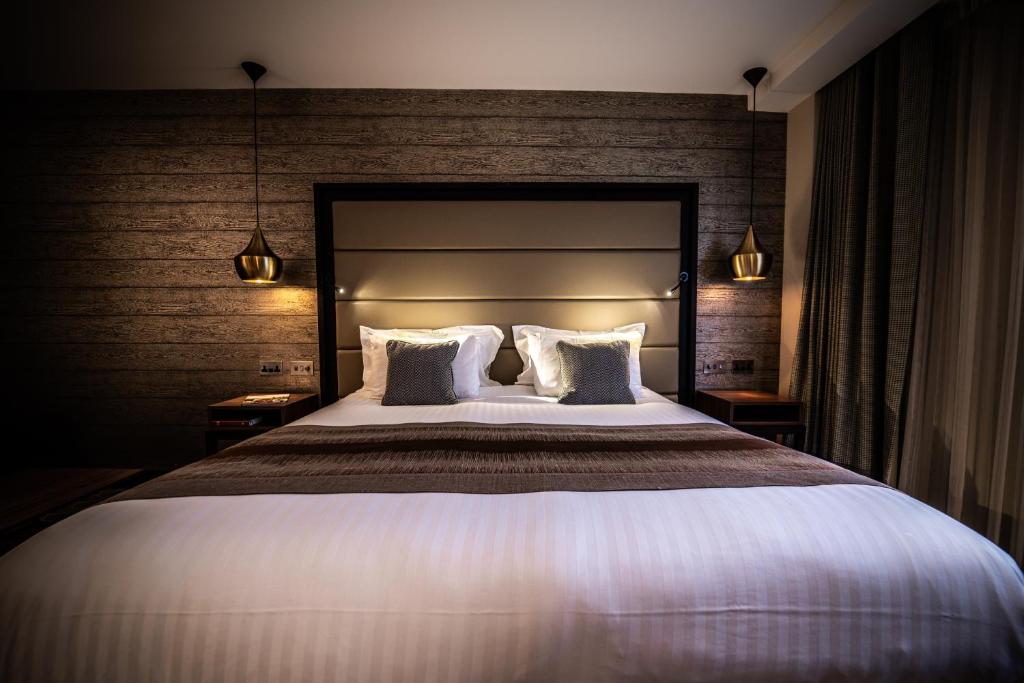 um quarto com uma cama grande e 2 almofadas em The Warwickshire Hotel and Country Club em Warwick