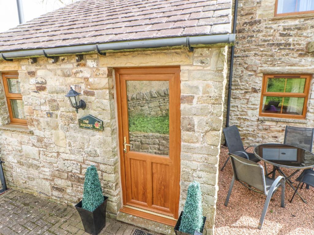 een stenen cottage met een houten deur en een tafel bij The Hayloft in Alston