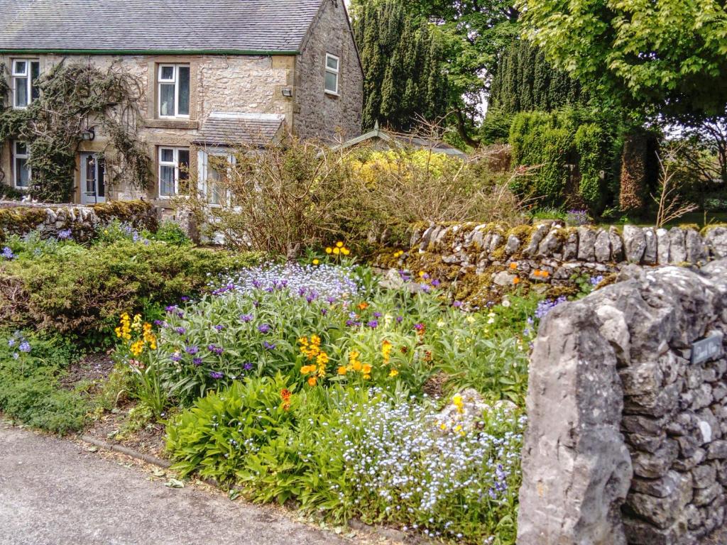 a garden with flowers in front of a stone wall at Church View in Hartington