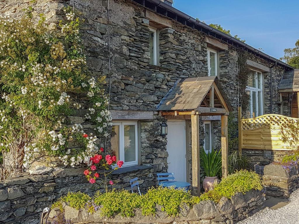 a stone house with a white door and flowers at Pheasant Cottage in Grange Over Sands