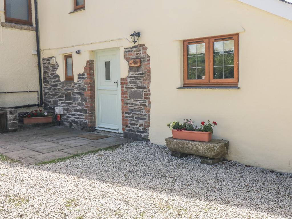 a white house with a door and two potted plants at Lower West Curry Cottage in Launceston