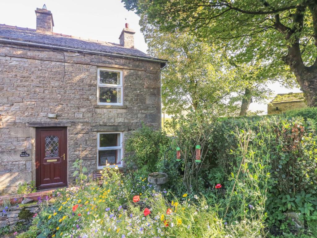a stone house with a garden in front of it at Sycamore Cottage in Cotterdale