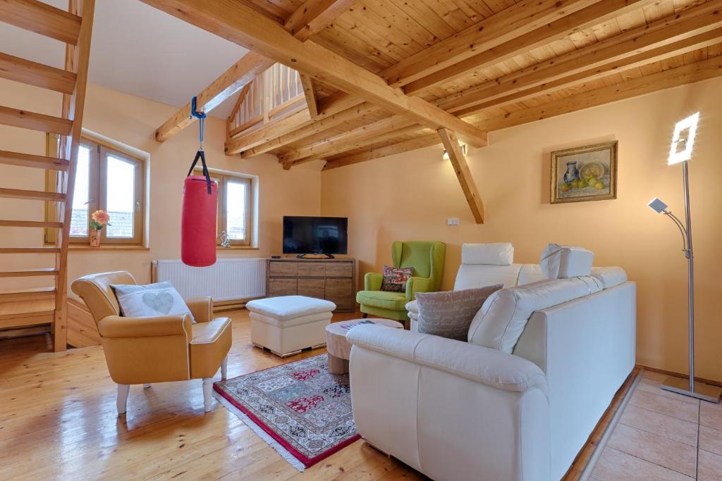 una sala de estar con muebles blancos y techos de madera. en Romance Ubytování, en Jindřichův Hradec