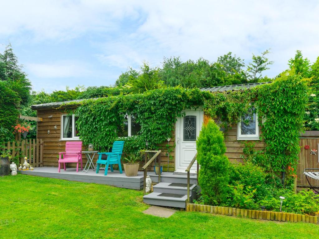 The Log Cabin في Adforton: منزل صغير مع كراسي و ivy