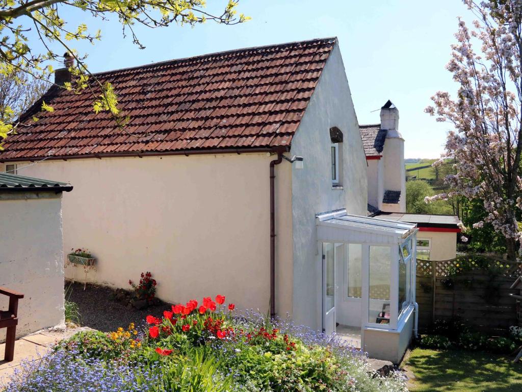 a white house with a window and some flowers at The Cottage in Bideford