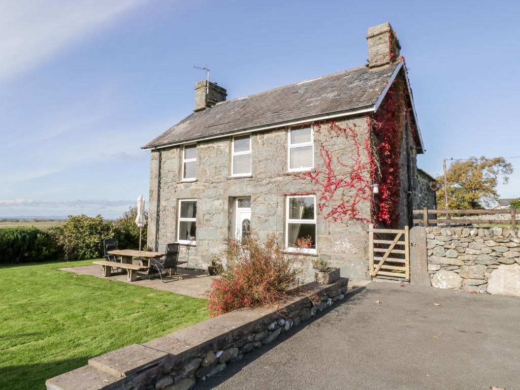 une ancienne maison en pierre avec une table de pique-nique devant elle dans l'établissement Tyddyn, à Dyffryn