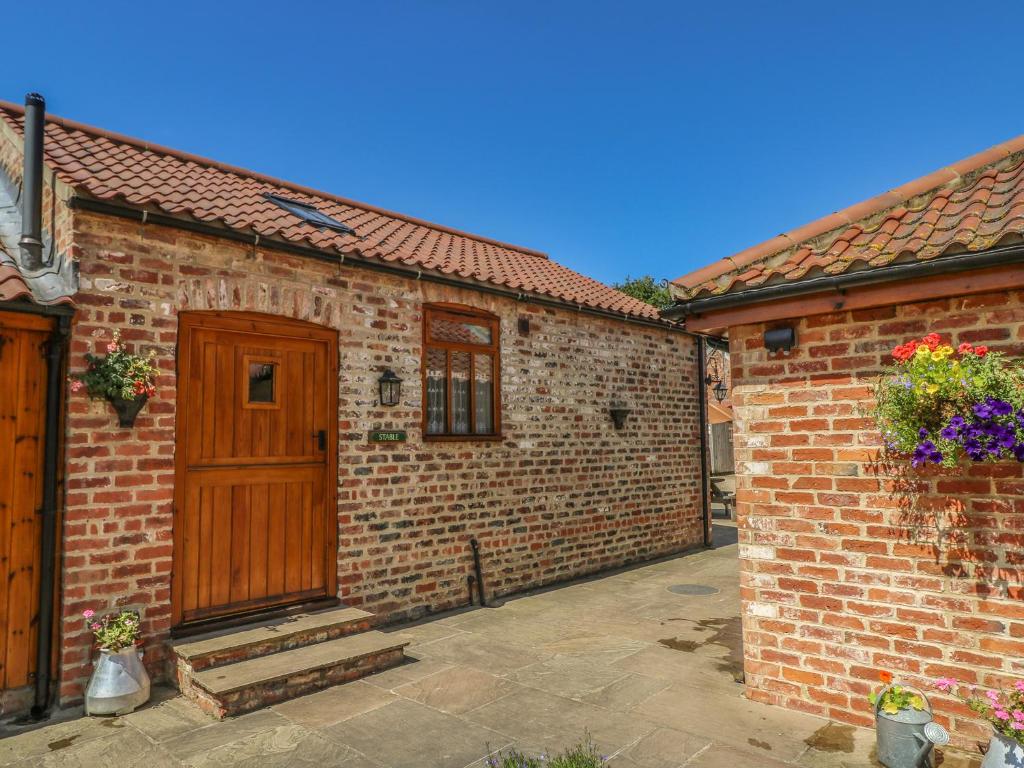 uma casa de tijolos com uma porta de madeira e um pátio em Stable Cottage em Thirsk