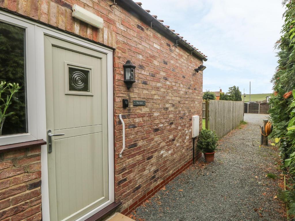 a brick house with a white door and a driveway at The Barn in High Catton
