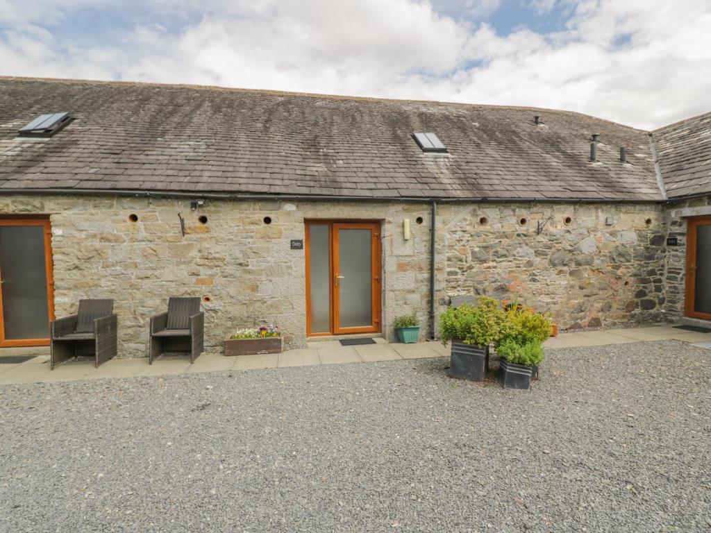 a stone building with two chairs in front of it at The Dairy in Newton Stewart