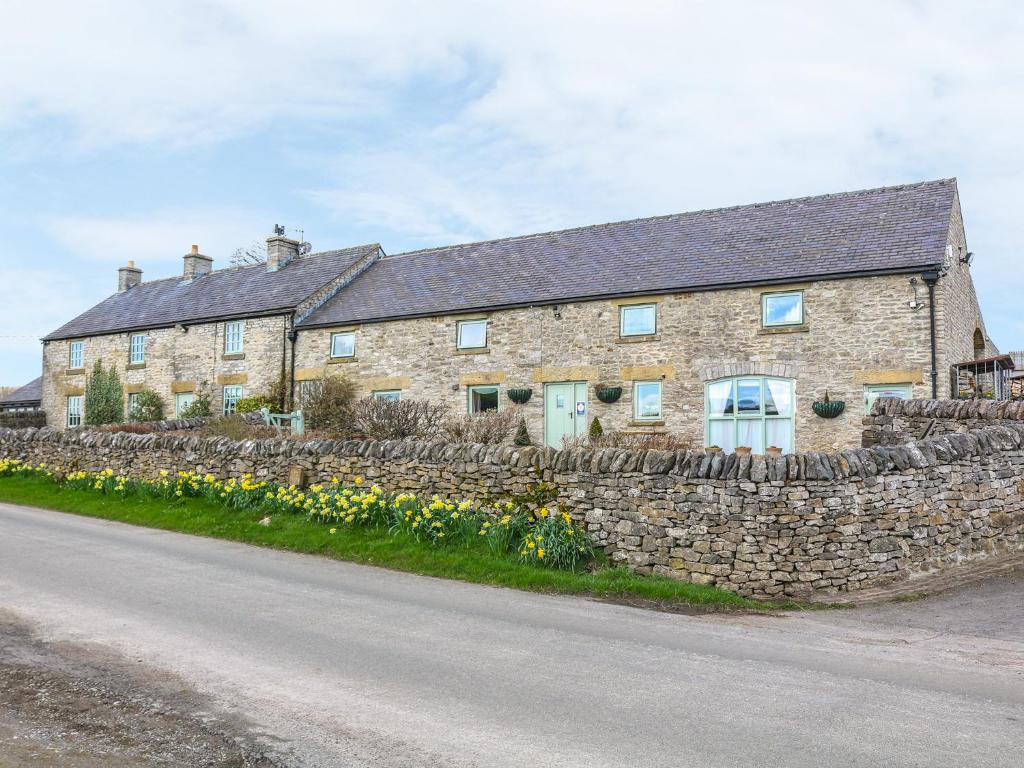 uma casa de pedra com uma parede de pedra e flores em The Dairy em Buxton