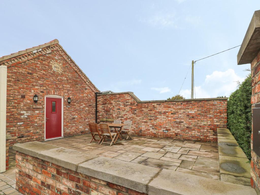 un patio con mesa y sillas frente a una pared de ladrillo en Apple Tree Cottage, en Dunnington