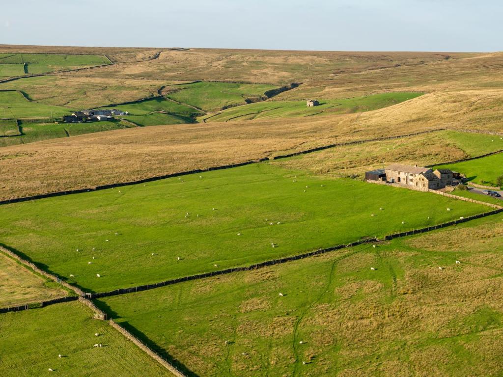 an aerial view of a green field with a house in it at The Retreat in Hebden Bridge