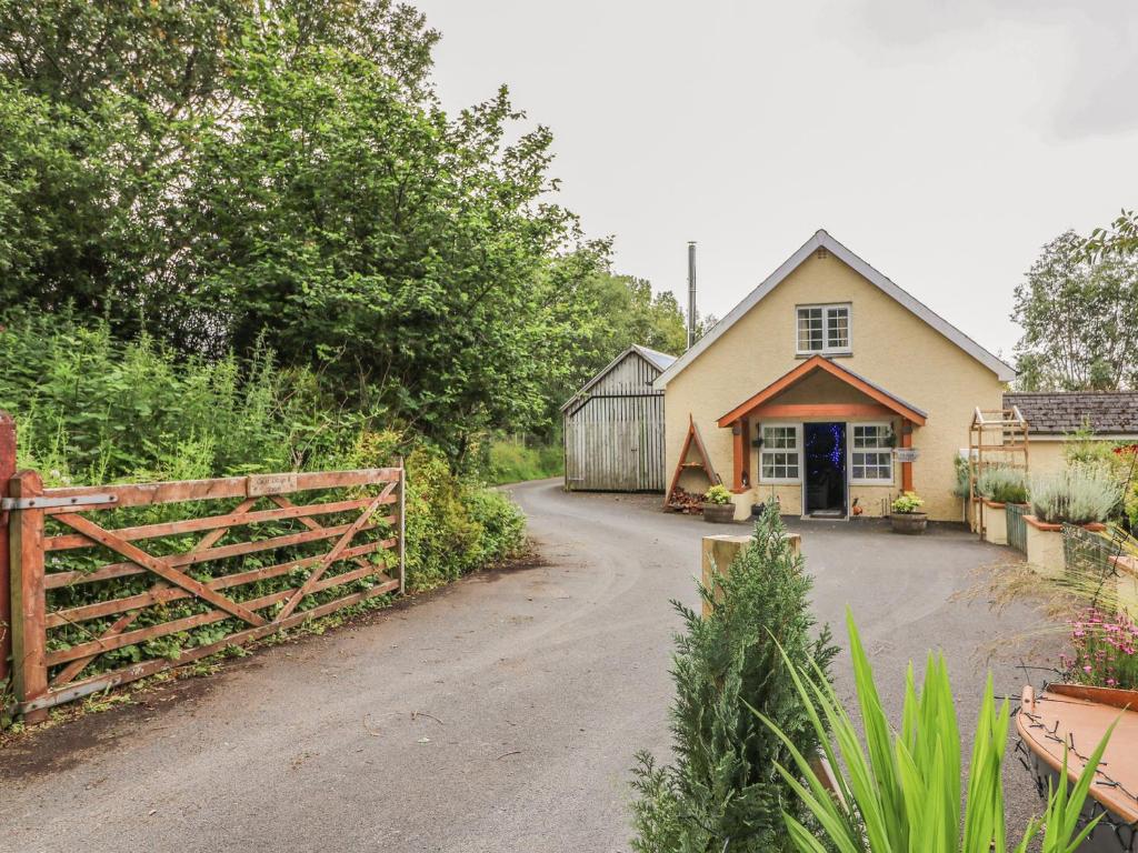 a house with a wooden gate and a driveway at Cariad Cottage in Cilcennin