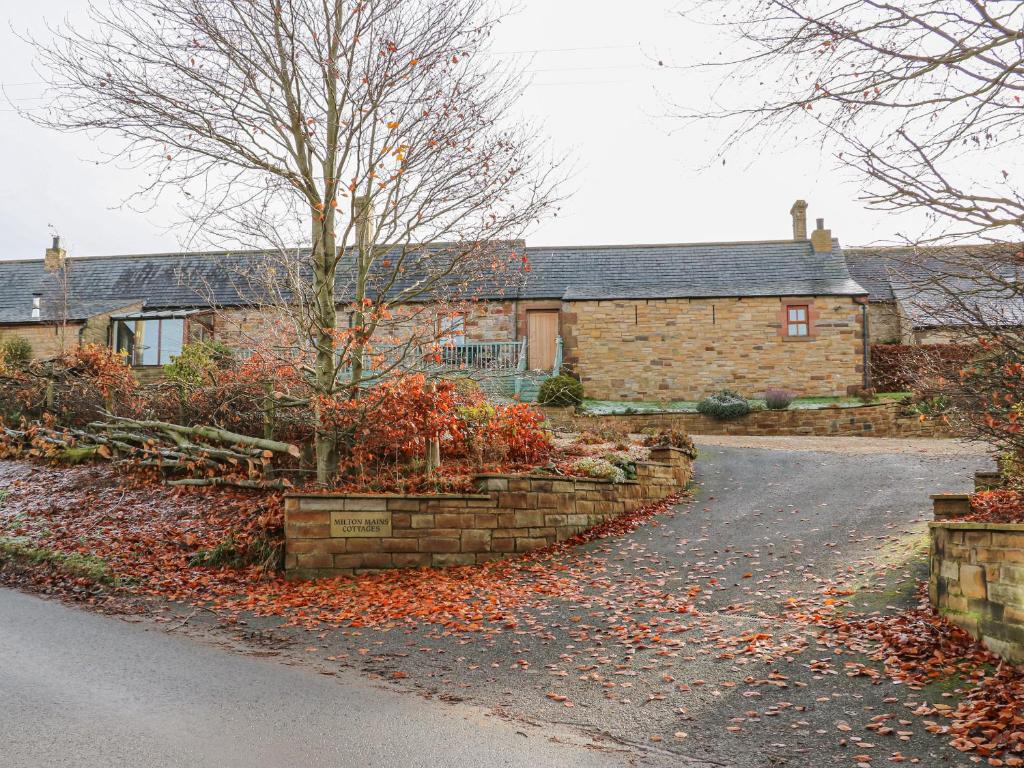 a house with a stone wall in front of a driveway at Swallow Cottage in Brampton
