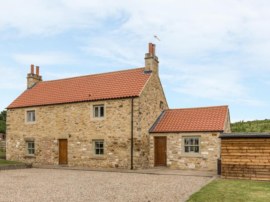 una antigua casa de piedra con techo rojo en Orchard Cottage, en Durham