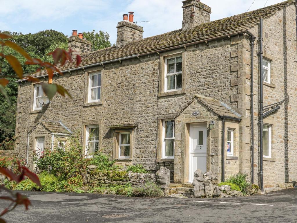an old stone house with a white door at Lavender Cottage in Threshfield