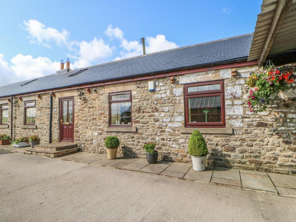 a stone house with potted plants in front of it at Grove Cottage in Copley