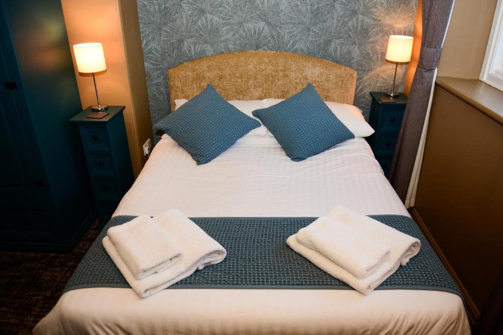 a bedroom with a bed with blue and white pillows at Plough Inn in Morpeth