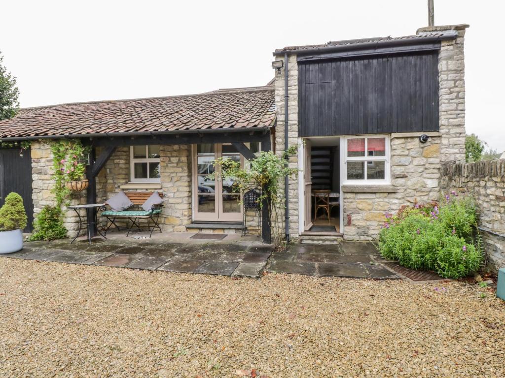 a stone cottage with a black roof and a patio at The Coach House in Bristol