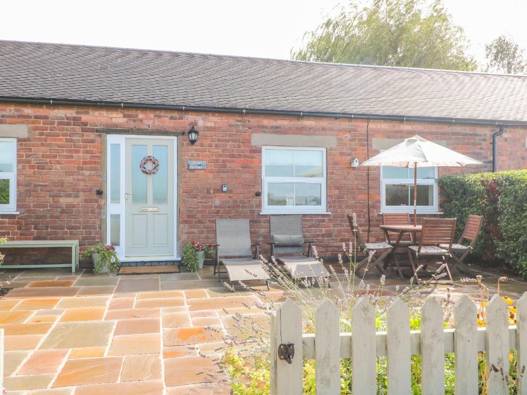 a brick house with a table and an umbrella at The Byre in Ashbourne