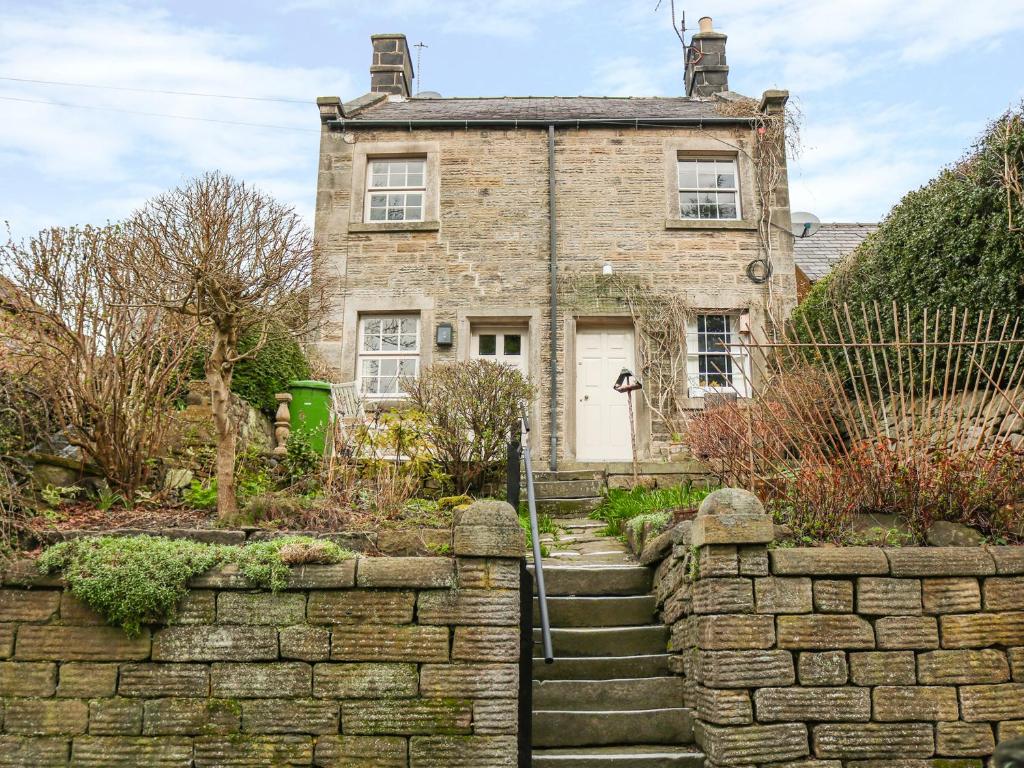 una antigua casa de ladrillo con una pared de piedra en Ash Cottage en Bakewell