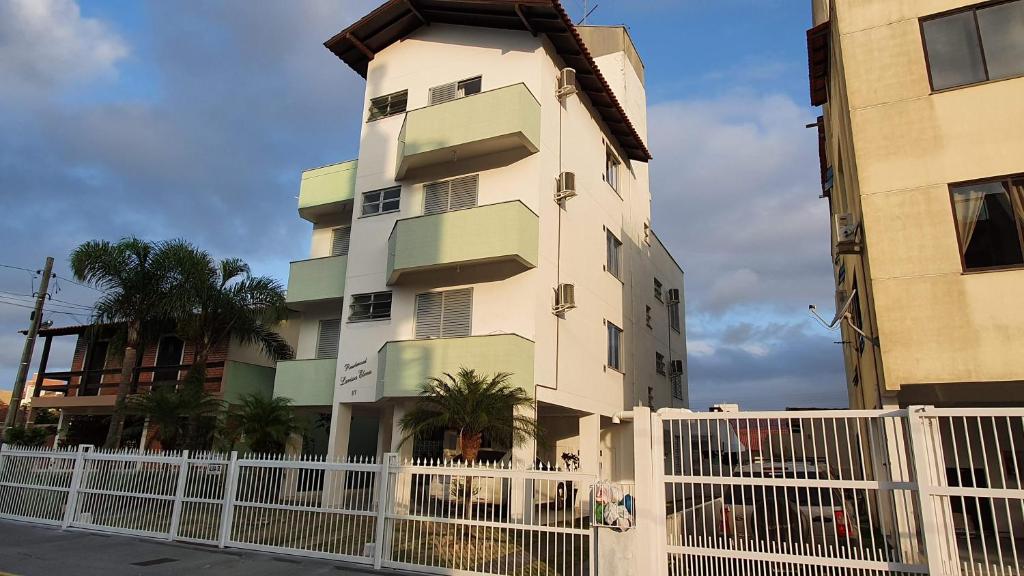 un edificio alto con una valla blanca delante de él en Residencial Larissa Elena, en Florianópolis