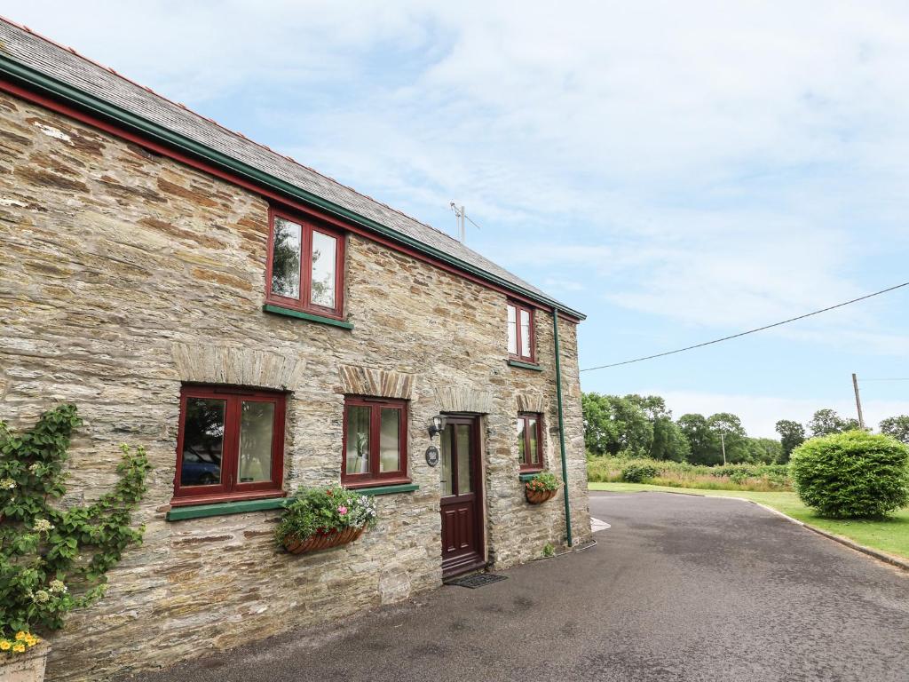 a stone house with red windows and a driveway at Oak Cottage in Llandysul